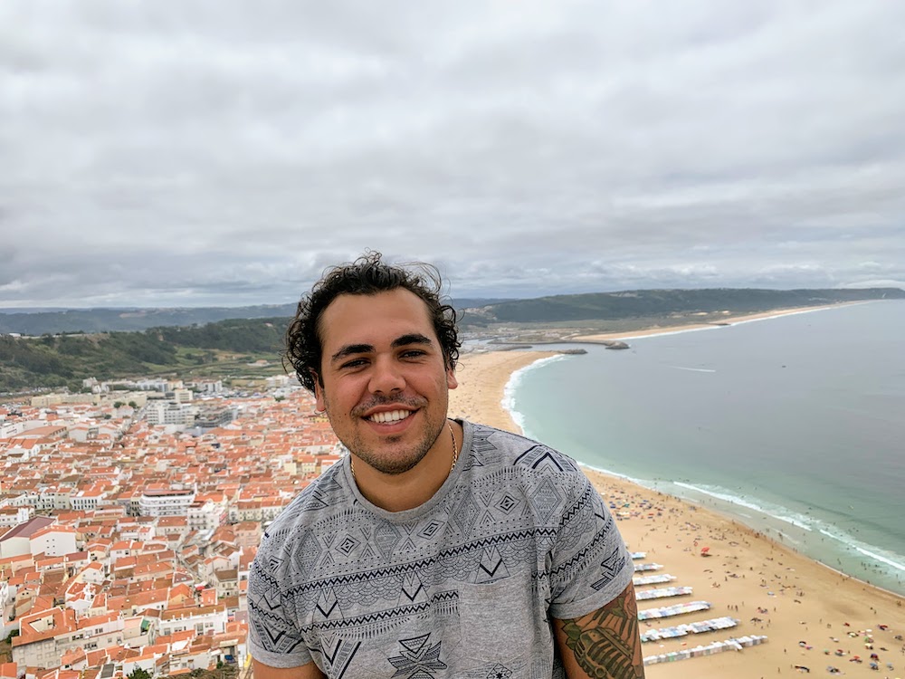 This picture is about a headshot of Chris Dias in Nazare with the beach in the background
